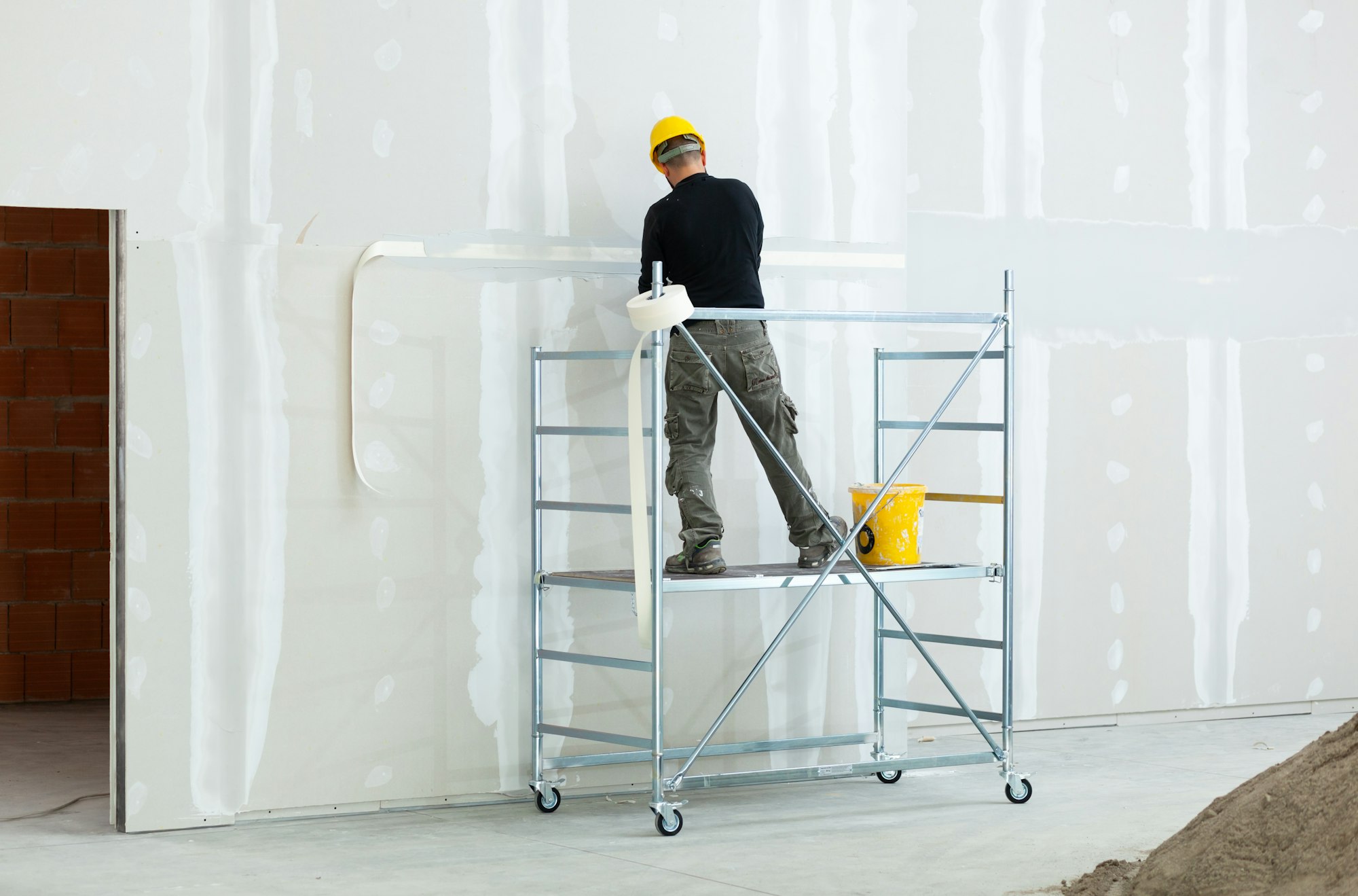 worker plastering gypsum board wall.